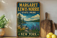 A vintage-style metal sign for Margaret Lewis Norrie State Park in New York, featuring a scenic landscape with a lake, mountains, and flowers.