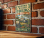 A vintage-style metal sign for Marjorie Kinnan Rawlings Historic State Park in Florida, featuring a typewriter and palm trees.