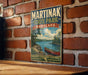 A vintage-style metal sign for Martinak State Park in Maryland, featuring a scenic image of a lake and a canoe, mounted on a brick wall.