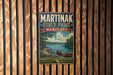 A vintage metal sign for Martinak State Park, Maryland, featuring a scenic image of a lake and a canoe, mounted on a wooden wall.