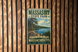 A vintage metal sign for Massasoit State Park, featuring a scenic landscape with pine trees, a lake, and mountains.