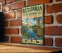 A vintage-style metal sign for the Mattawoman Natural Environment Area in Maryland, featuring an illustration of a heron and a river.