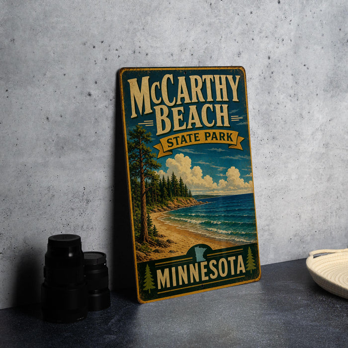 A vintage-style metal sign for McCarthy Beach State Park in Minnesota, featuring a scenic landscape with a beach, pine trees, and a lake.