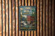 A vintage metal sign for McConnells Mill State Park in Pennsylvania, featuring a red brick building with a watermill and a waterfall.