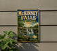 A vintage-style metal sign for McKinney Falls State Park in Texas, featuring a scenic illustration of the waterfall surrounded by lush greenery.