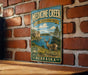 A vintage-style metal sign for Medicine Creek State Recreation Area in Nebraska, featuring a scenic illustration of a deer in a grassy field with a lake in the background.