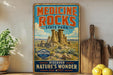 a vintage-style sign for Medicine Rocks State Park, with a desert landscape and rock formations depicted on it. The sign is displayed on a shelf next to a wooden cutting board and a potted plant.