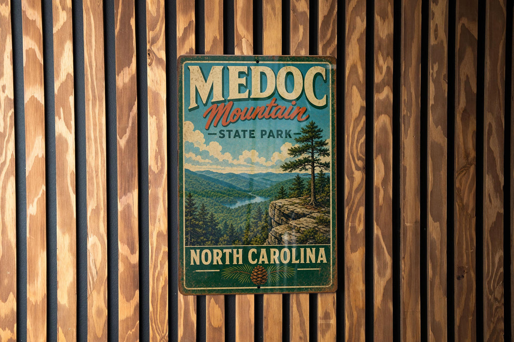 A vintage metal sign for Medoc Mountain State Park in North Carolina, featuring a scenic mountain landscape with pine trees and a cliff.