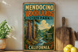 A vintage-style metal sign for Mendocino Woodlands State Park in California, featuring a scenic illustration of the park's forests and a river.