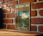 A vintage metal sign for Mendocino Woodlands State Park in California, featuring a scenic illustration of the park's natural beauty.