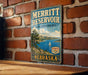 A vintage metal sign for the Merritt Reservoir State Recreation Area in Nebraska, featuring a scenic landscape with a lake, mountains, and a sailboat.