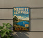 A vintage metal sign for the Merritt Reservoir State Recreation Area in Nebraska, featuring a scenic landscape with a lake, mountains, and a sailboat.