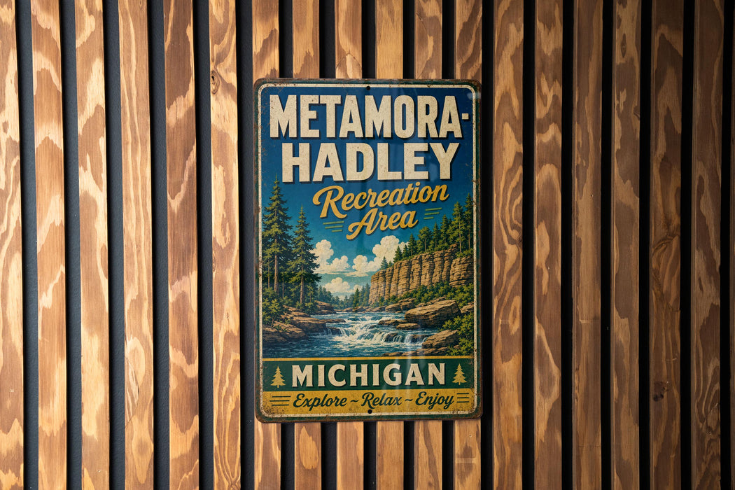 A vintage metal sign for the Metamora-Hadley Recreation Area in Michigan, featuring a scenic landscape with a waterfall and pine trees.