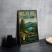 A vintage-style metal sign for Milan Hill State Park, featuring a scenic landscape with mountains, pine trees, and a lake.