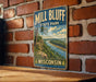 A vintage-style metal sign for Mill Bluff State Park in Wisconsin, featuring a scenic landscape with a river and forest.
