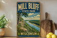 A vintage-style sign for Mill Bluff State Park in Wisconsin, featuring a scenic landscape with a river and forest.