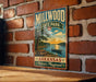 A vintage metal sign for Millwood State Park in Arkansas, featuring a scenic landscape with a lake, trees, and a sunset.