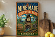 A vintage-style metal sign for the Mine-Made Adventure Park in Kentucky, featuring an illustration of a zip line and a person hanging from a rope bridge.