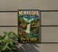 A vintage-style metal sign for Minnesota State Park, featuring a waterfall and lush greenery, is displayed on a wall.