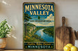 A vintage-style sign for Minnesota Valley State Recreation Area, featuring a scenic landscape with a river, mountains, and lush greenery.