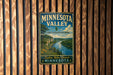 A vintage Minnesota Valley sign is displayed on a wooden wall, inviting visitors to explore, relax, and connect with the state's natural beauty.