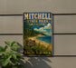 A vintage metal sign for Mitchell State Park in Michigan, featuring a scenic landscape with pine trees, a beach, and a lake.