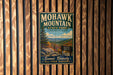 A vintage metal sign for Mohawk Mountain State Park in Connecticut, featuring a scenic mountain landscape with a sign indicating the elevation of 1,860 feet.