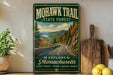 A vintage-style metal sign for the Mohawk Trail State Forest in Massachusetts, featuring a scenic mountain landscape with a winding road.