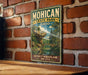A vintage-style metal sign for Mohican State Park in Ohio, featuring a scenic landscape with a bridge and trees.