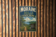 A vintage-style metal sign for Moraine Hills State Park in Illinois, featuring a scenic landscape with a path leading to a waterfall.