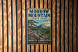 A vintage metal sign for Morrow Mountain State Park, featuring a scenic mountain landscape with pine trees and pink flowers.