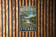 A vintage metal sign for Mother Neff State Park in Texas, featuring a scenic landscape with a waterfall and lush vegetation.