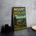 A vintage metal sign for Mount Pisgah State Park in Pennsylvania, featuring a scenic landscape with a cliff and flowers.