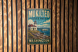 A vintage metal sign for Mukilteo State Park in Washington, featuring a lighthouse and a boat on the water.
