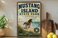 A vintage-style sign for Mustang Island State Park in Texas, featuring a horse running on a beach with a palm tree in the background.