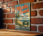 A vintage-style metal sign for Myrtle Beach State Park in South Carolina, featuring a palm tree and beach scene, is displayed on a brick wall.
