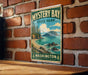 A vintage-style metal sign for Mystery Bay State Park in Washington, featuring a scenic landscape with a beach, mountains, and a body of water.