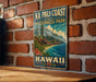 A vintage-style metal sign displaying the text "NA PALI COAST STATE WILDERNESS PARK HAWAII" with a mountain landscape and ocean scene.
