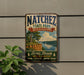 A vintage-style sign for Natchez State Park, Mississippi, featuring a scenic landscape with a river, cliffs, and trees.