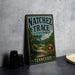 A vintage metal sign for Natchez Trace State Park in Tennessee, featuring a scenic illustration of a winding road surrounded by trees and mountains.