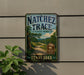 A vintage-style sign for Natchez Trace State Park in Tennessee, featuring a scenic landscape with a winding road and lush greenery.