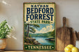 A vintage-style sign for Nathan Bedford Forrest State Park in Tennessee, featuring a scenic landscape with a lake and mountains.