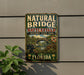 A vintage metal sign for Natural Bridge Battlefield Historic State Park in Florida, featuring a scenic illustration of the park and its surroundings.