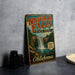 A vintage-style sign for Natural Falls State Park in Oklahoma, featuring a waterfall and lush greenery.
