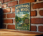 A vintage-style metal sign fornersand-big woods state park in Minnesota, featuring a scenic illustration of a waterfall and forest.