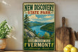 A vintage-style sign for New Discovery State Park, featuring a scenic landscape with mountains, a lake, and pine trees.