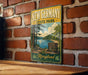 A vintage-style metal sign for New Germany State Park, featuring a scenic landscape with a lake and forest.