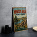 A vintage-style metal sign welcoming visitors to Newton Hills State Park in South Dakota, featuring a scenic landscape with a lake and mountains.