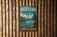 A vintage-style metal sign for Nick's Lake State Park in New York, featuring a scenic landscape with a lake, mountains, and pine trees.