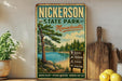 A vintage-style metal sign for Nickerson State Park in Massachusetts, featuring a scenic landscape with a lake, pine trees, and a sign indicating various outdoor activities available at the park.